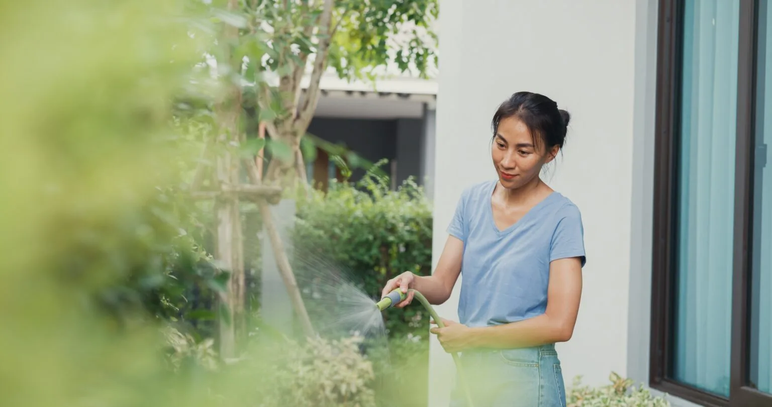 cheerful-happy-asian-girl-use-garden-hose-watering