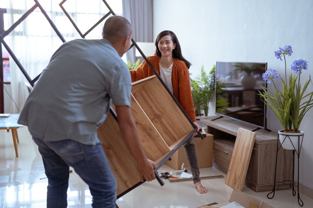 man and woman rearranging furniture in their condo unit