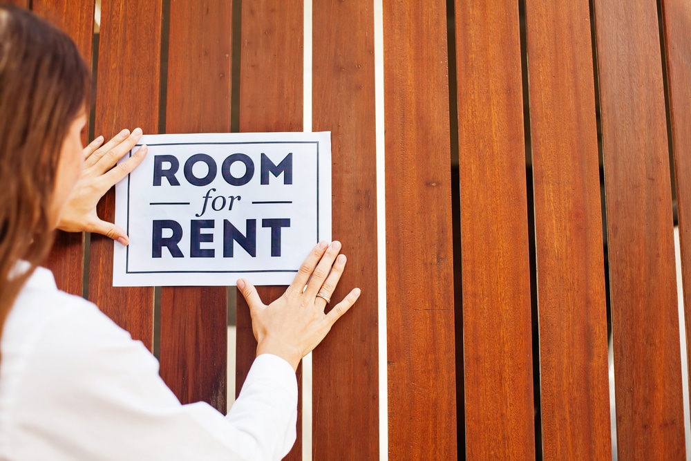 a photo of an individual placing a "room for rent" sign.