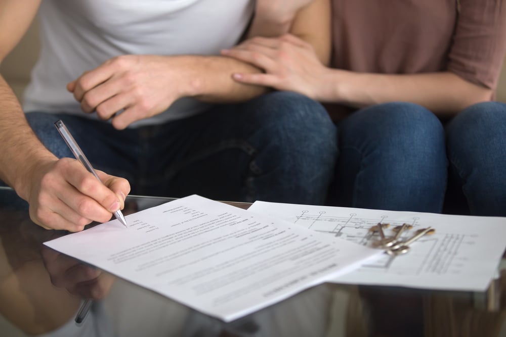 a photo of a couple signing a contract to buy a home.