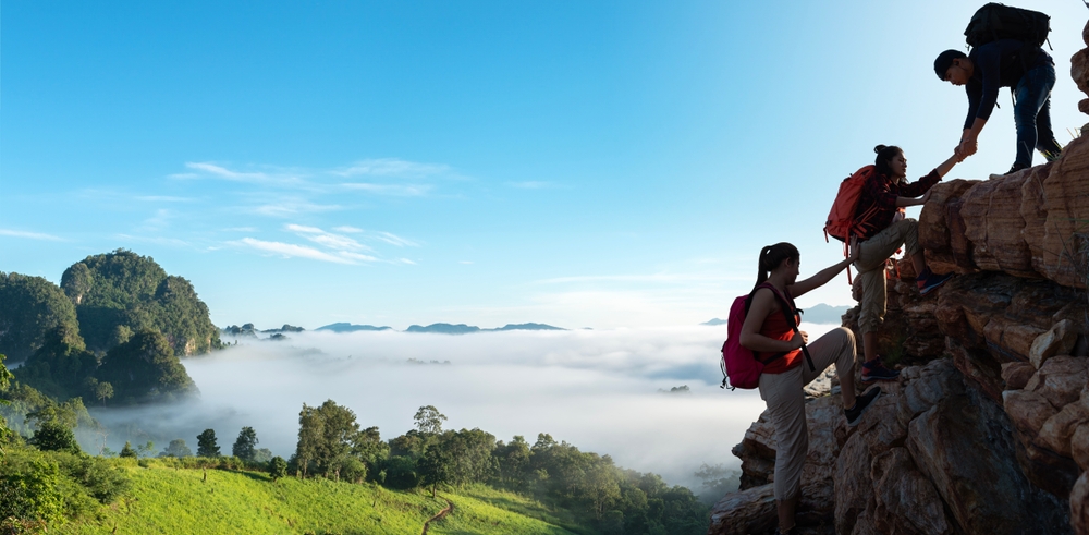 hikers helping each other climb a mountain banner