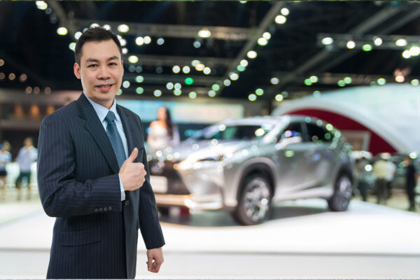 Happy car salesman on auto show blurred background, transportation concept
