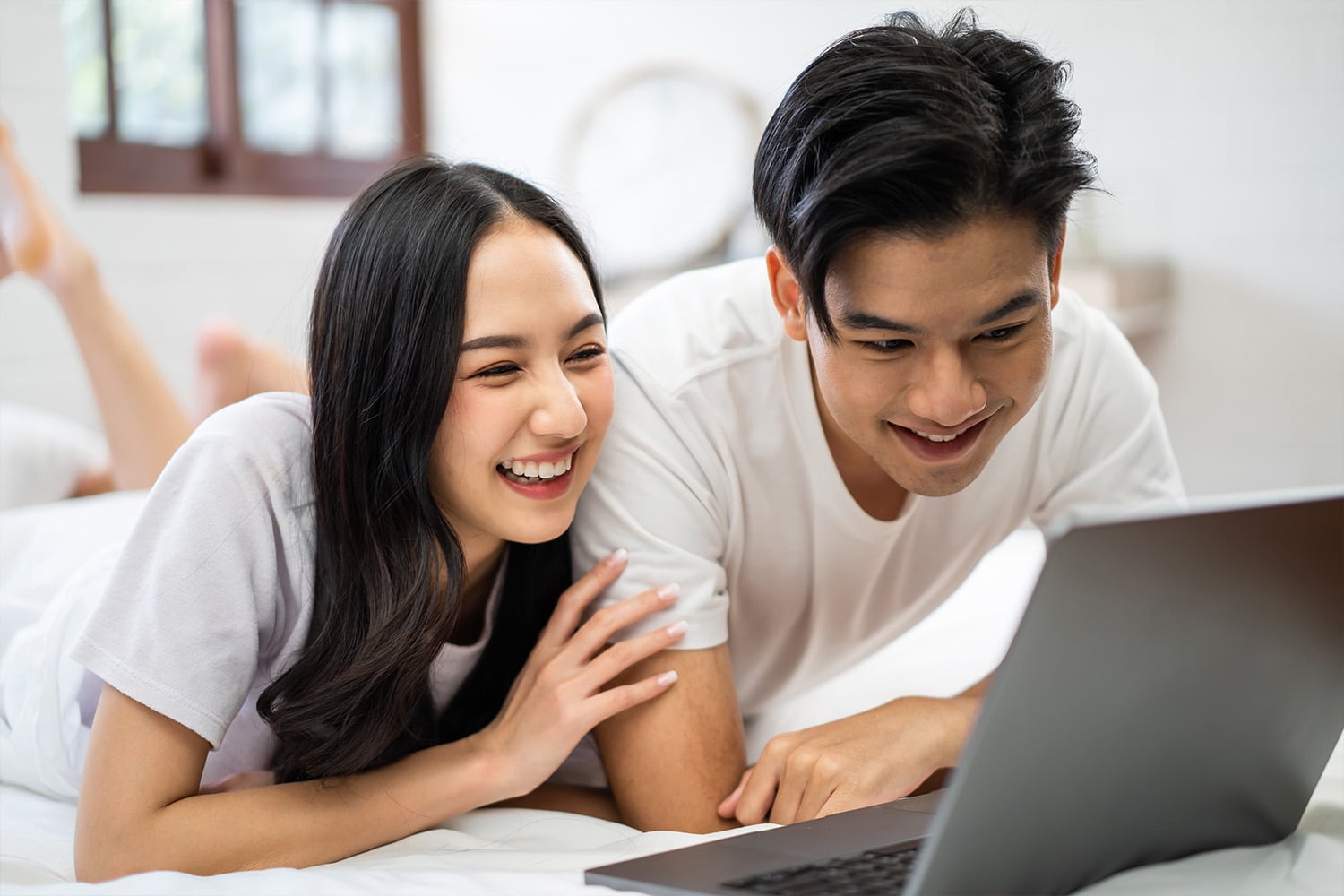 asian attractive woman using laptop on bed with husband