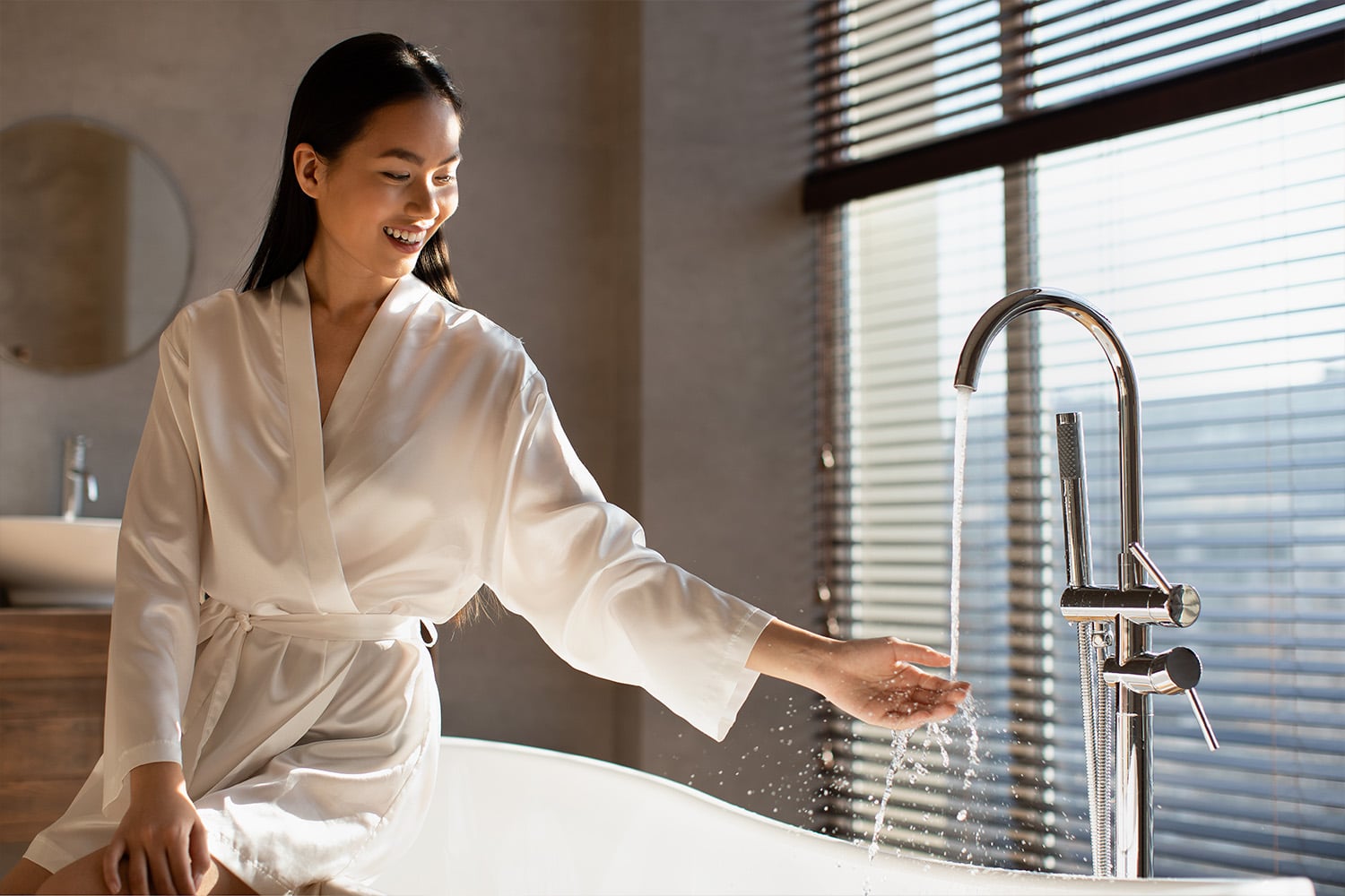 woman checking water temperature on bathtub